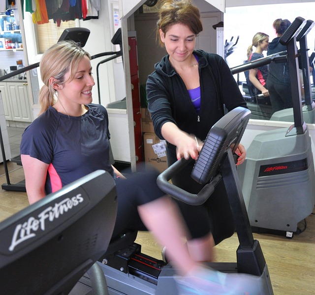 woman instructing another woman on a bicycle at the gym
